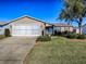 Front view of a tan house with garage and landscaping at 2009 Claudio Ln, The Villages, FL 32159