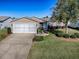 Tan single story home exterior with a two car garage and mature landscaping at 2009 Claudio Ln, The Villages, FL 32159