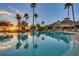 Resort-style pool with palm trees and clubhouse at sunset at 3898 Beacon Ridge Way, Clermont, FL 34711