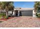 Home exterior featuring a dark gray garage and landscaping at 4992 Big Cypress St, Oxford, FL 34484