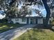 Front view of a ranch home with a driveway and large oak trees at 609 Scenic St, Leesburg, FL 34748