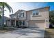 Two-story house with tan exterior, two-car garage, and palm trees at 702 Skyridge Rd, Clermont, FL 34711