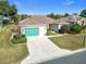 Single-story home with green garage door, landscaping, and paved driveway at 9397 Se 124Th Pl, Summerfield, FL 34491