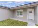 White front door and window with covered porch and grassy area at 1 Malauka Pass Ct, Ocklawaha, FL 32179