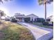 Inviting single-story home with a brick driveway, well-maintained lawn, and mature palm tree at 1204 Maria Ct, Lady Lake, FL 32159