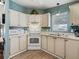 White kitchen with ample counter space and cabinets, featuring light wood flooring at 1210 Tarpon Ln, The Villages, FL 32159