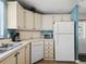 Corner view of kitchen, white appliances and cabinets, light wood flooring at 1210 Tarpon Ln, The Villages, FL 32159