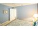 Bright bedroom with blue walls featuring a bed, nightstand with lamp, and open door leading to another room at 1541 Fenimore Ln, The Villages, FL 32162