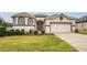 House exterior showcasing a two-car garage and attractive landscaping at 16904 Se 110Th Court Rd, Summerfield, FL 34491