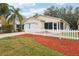 Tan house with white picket fence, landscaped yard, and two-car garage at 17461 Se 93Rd Retford Ter, The Villages, FL 32162