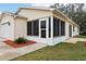 Side view of a tan house with a screened porch and landscaping at 17461 Se 93Rd Retford Ter, The Villages, FL 32162