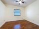 This bedroom boasts hardwood floors, a ceiling fan, and a window bringing in natural light at 2209 Stonebridge Way, Clermont, FL 34711