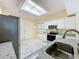 Well-lit kitchen with granite counters, stainless steel appliances, and skylight overhead at 2209 Stonebridge Way, Clermont, FL 34711