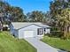 Aerial view of a light blue house with a driveway and landscaping at 26548 Deuce Ct, Leesburg, FL 34748