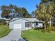 Front view of a light blue house with a palm tree and a green lawn at 26548 Deuce Ct, Leesburg, FL 34748