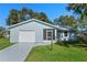 Front view of a light blue house with a garage and a palm tree at 26548 Deuce Ct, Leesburg, FL 34748