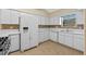 Galley kitchen with white cabinets, tile floors and appliances at 26912 Tanner St, Leesburg, FL 34748