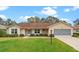 Tan one-story house with brown roof, landscaping, and a screened garage at 26913 Racquet Cir, Leesburg, FL 34748