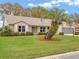 Beautiful single-story home featuring a lush green lawn, palm tree, landscaped garden, and neutral-colored exterior at 26913 Racquet Cir, Leesburg, FL 34748