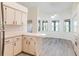 Open kitchen featuring light wood cabinets, a breakfast bar, and modern gray laminate floors extending to a dining area at 26913 Racquet Cir, Leesburg, FL 34748