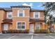 Two-story townhome with orange exterior, white trim, and landscaping at 2713 Impala Ln, Kissimmee, FL 34746