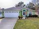 Green house with white garage door and landscaping at 30111 Pga Dr, Mount Plymouth, FL 32776