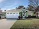 Green house with a white two-car garage and manicured lawn at 30111 Pga Dr, Mount Plymouth, FL 32776