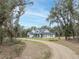 Modern farmhouse exterior with a long driveway and landscaping at 3493 Edwards Road, Lady Lake, FL 32159