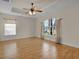 Bright bedroom with wood look tile floors, tray ceiling, fan and large arched window at 35808 Rose Moss Ave, Leesburg, FL 34788