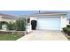 House exterior featuring a white garage door, landscaping, and a white picket fence at 3621 Amelia Ave, The Villages, FL 32162