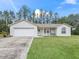 Single-story house with white exterior, two-car garage, and grassy yard at 39727 Redbud Rd, Lady Lake, FL 32159