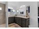 Double vanity bathroom with gray cabinets and shower at 4923 Lawler Loop, The Villages, FL 32163