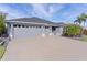 Gray three-car garage home with landscaped yard and palm trees at 4923 Lawler Loop, The Villages, FL 32163