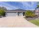 Gray three-car garage home with landscaped yard and palm trees at 4923 Lawler Loop, The Villages, FL 32163