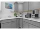 Well-lit kitchenette features gray cabinetry, white countertops, and stainless appliances at 4923 Lawler Loop, The Villages, FL 32163