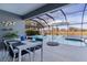 View of a screened-in pool with a dining table and chairs for outdoor entertaining near a pond at 4923 Lawler Loop, The Villages, FL 32163