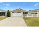 Beige house with white garage door and picket fence at 5415 Kate Ct, The Villages, FL 32163