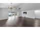 Bright living room with sliding glass doors to backyard, dark floors, and modern chandelier at 583 Arruda Ter, The Villages, FL 32162