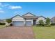 Two-story house with gray siding, two-car garage, and a brick driveway at 729 Calabria Way, Howey In The Hills, FL 34737