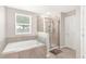 Bathroom with soaking tub, shower, and window at 848 Carmillion Ct, Groveland, FL 34736