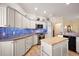 Modern kitchen with white cabinets, blue tile backsplash and stainless steel appliances at 848 Folsum Pl, The Villages, FL 32162