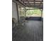 A relaxing screened back porch with rustic wood planks, seating, and serene wooded views at 10094 Sw 153Rd Ln, Dunnellon, FL 34432