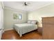 Cozy bedroom with wood floors, a ceiling fan, and a large window for natural light at 17664 Se 105Th Terrace, Summerfield, FL 34491