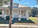 White house with gray shutters, front porch, and a tree in the foreground at 248 E Magnolia St, Groveland, FL 34736