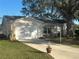 Single-story home with a white exterior, a two-car garage, and a well-maintained lawn at 24825 Pine Hl, Leesburg, FL 34748