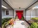 Covered entryway with red door, seating area, and potted plants at 27039 Racquet Cir, Leesburg, FL 34748