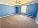 Spacious bedroom with blue walls, carpet flooring, and a bright window at 2707 Privada Dr, The Villages, FL 32162