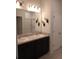 Bathroom featuring double sinks, granite countertops, a large mirror, vanity lighting, and neutral tile flooring at 37030 Lake Overlook Dr, Grand Island, FL 32735