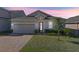 One-story home with gray siding, brick driveway, and landscaping at 571 Bellingham Way, Minneola, FL 34715