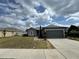 Well-maintained home showcases a tidy front yard, dark grey exterior, an attached garage and stone walkway at 5756 Lakeside Landings Blvd, Winter Haven, FL 33881